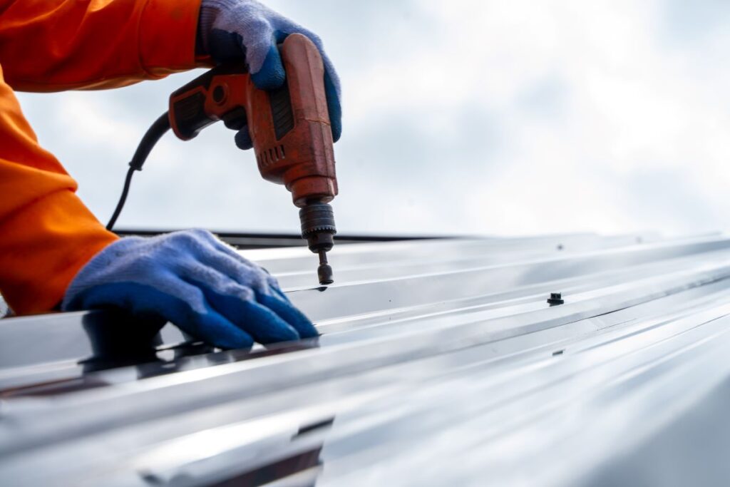roofer using nail gun to install metal roof