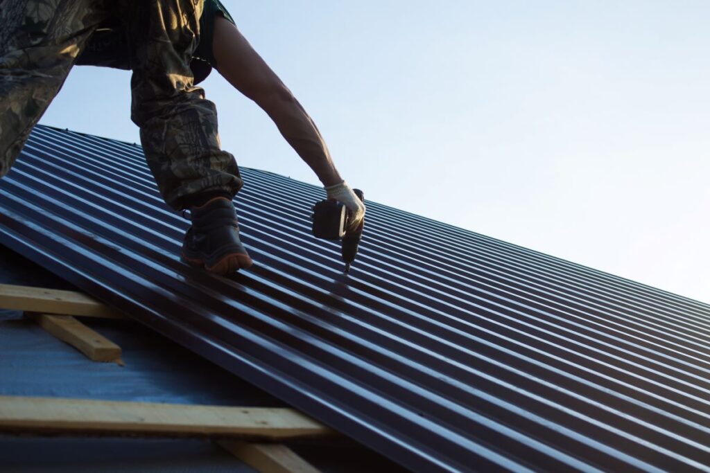 worker installing metal tiles on roof