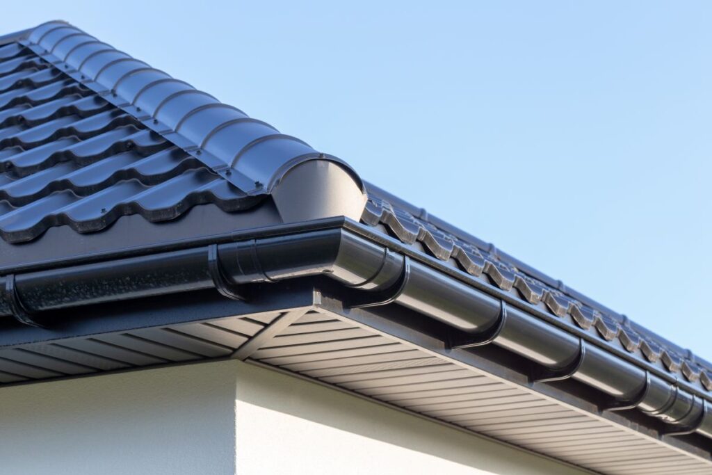 Corner of the new modern house with gutter, roof, wall under blue sky